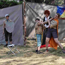 Eine Pfadfindergruppe ist lustig verkleidet und spielt auf einer improvisierten Bühne im Wald Schillers Handschuh