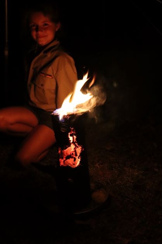 Eine Pfadfinderin sitzt hinter einer brennenden Schwedenfackel