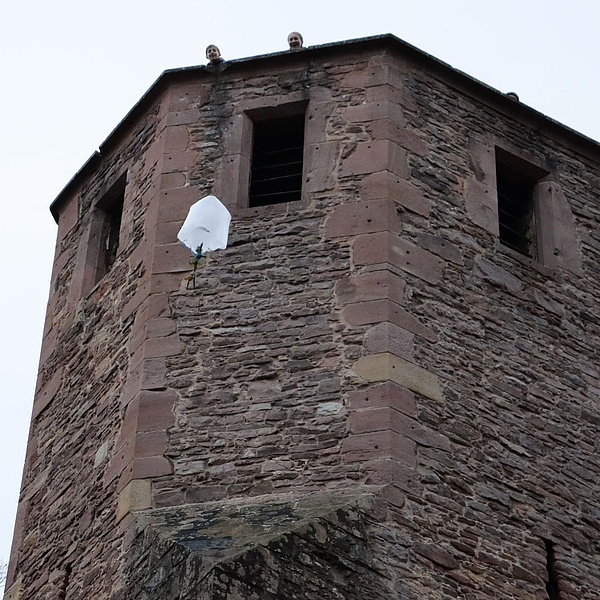 Ein selbstgebastelter Fallschirm fällt von einem hohen Turm herunter